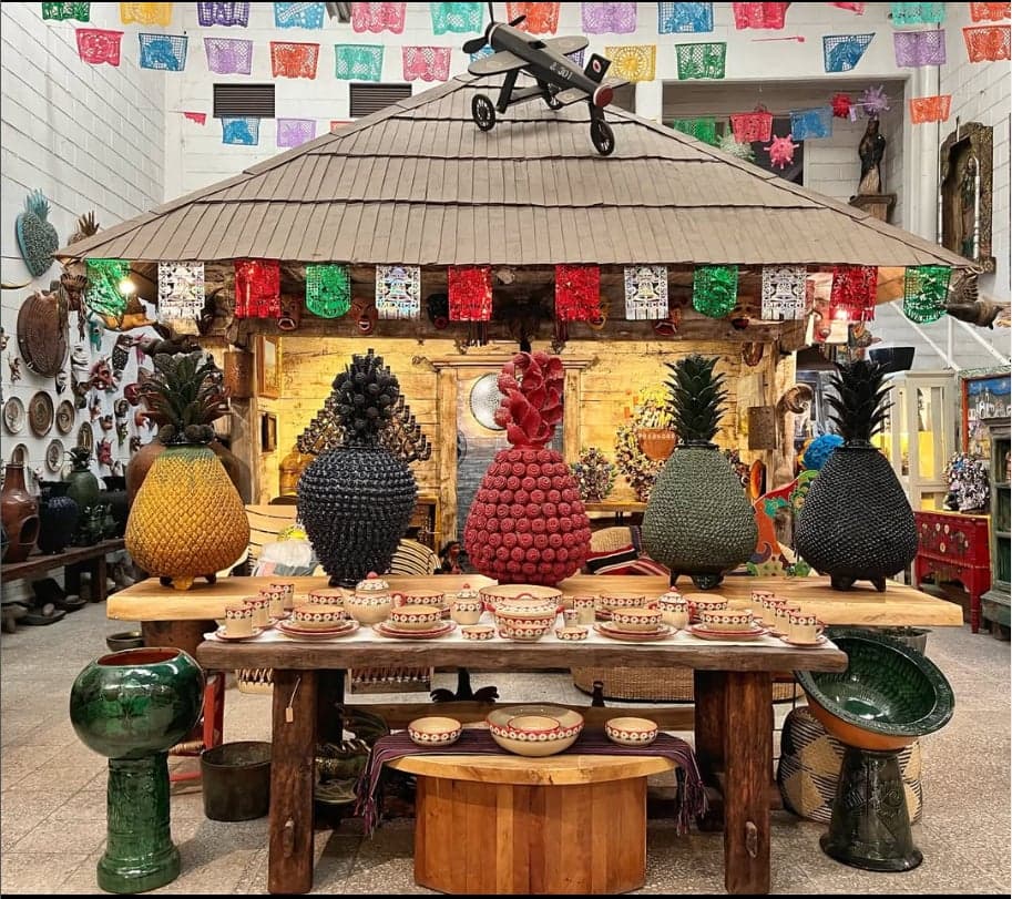 Interior de Casa Michoacana: palapa artesanal con piñas de cerámica vidriada y vajillas sobre mesas de madera, bajo papel picado